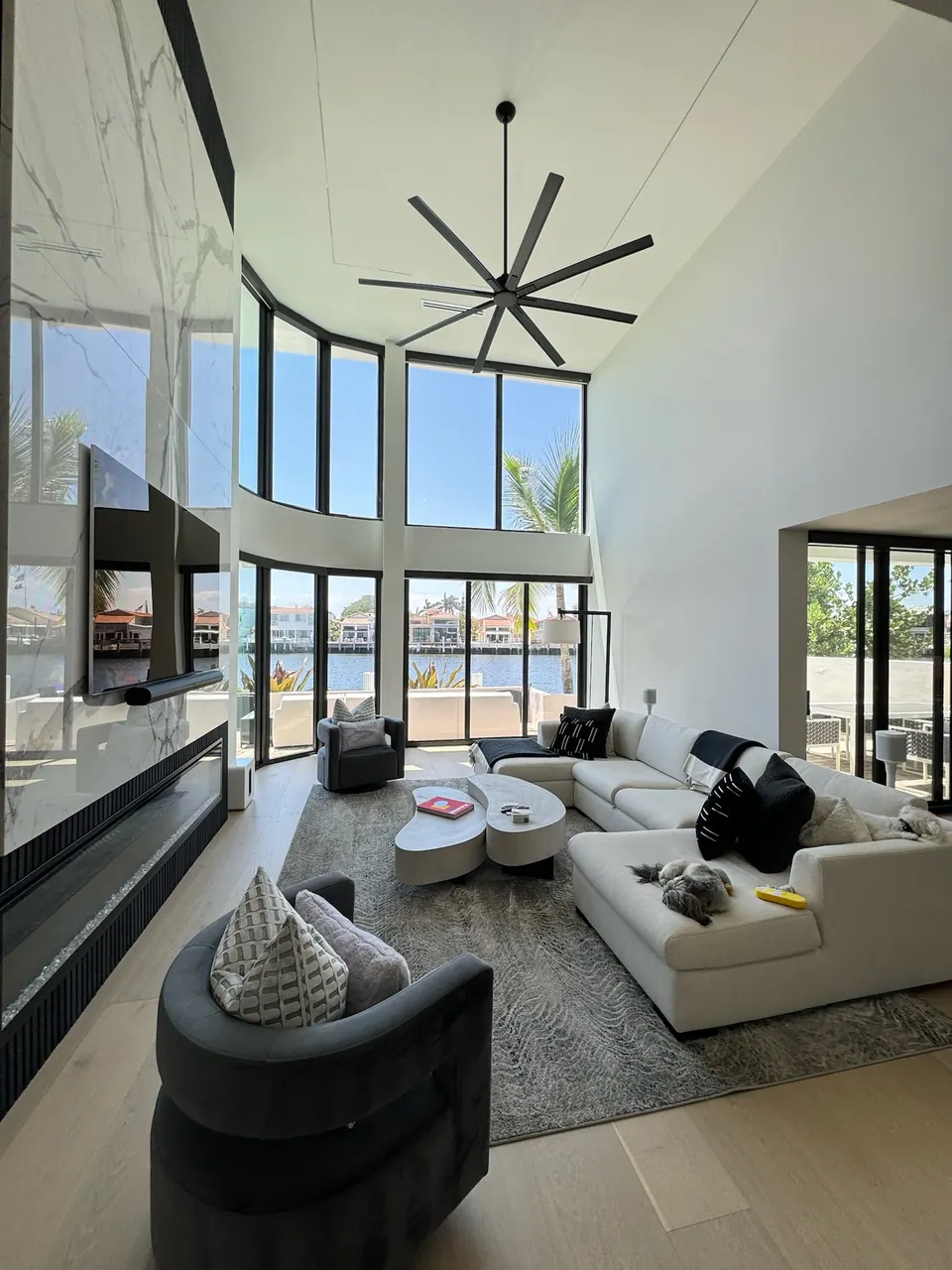 Light plank flooring under a double height living room with tall windows