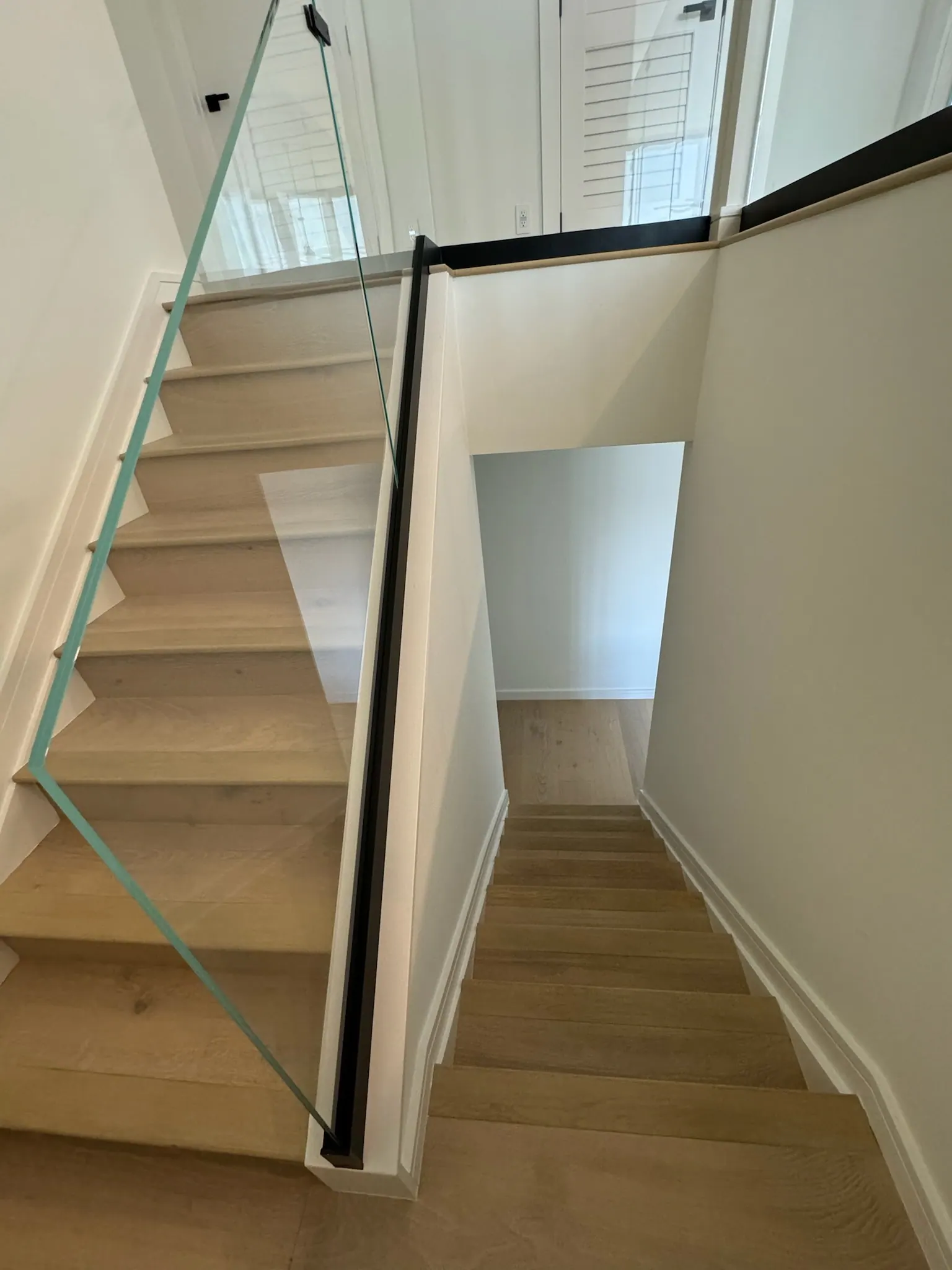 After: Stair treads and risers finished to match the main floor, with a glass rail